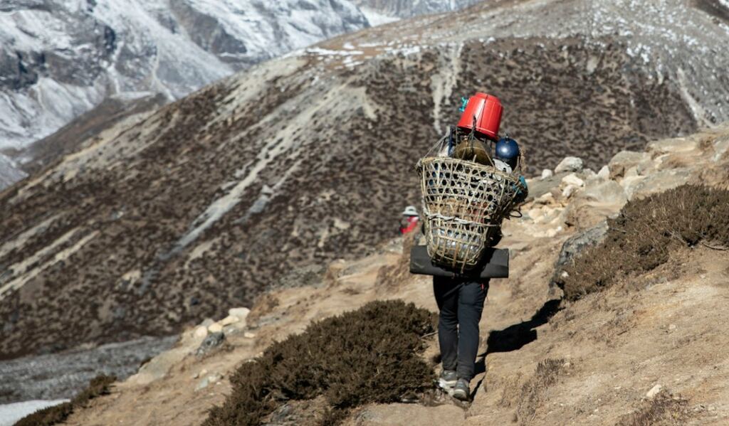 A mountain porter carrying a basket on a Himalayan trail in Nepal