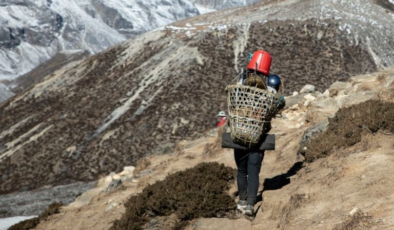 A mountain porter carrying a basket on a Himalayan trail in Nepal