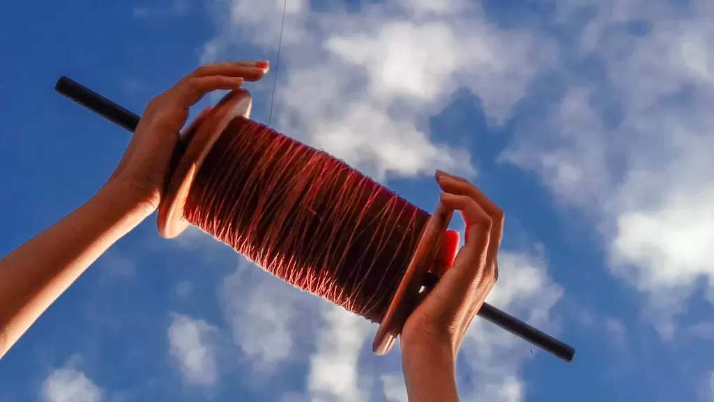 A kite-string spool beneath a cloudy sky, evoking traditional Dashain-season kite flying in Nepal