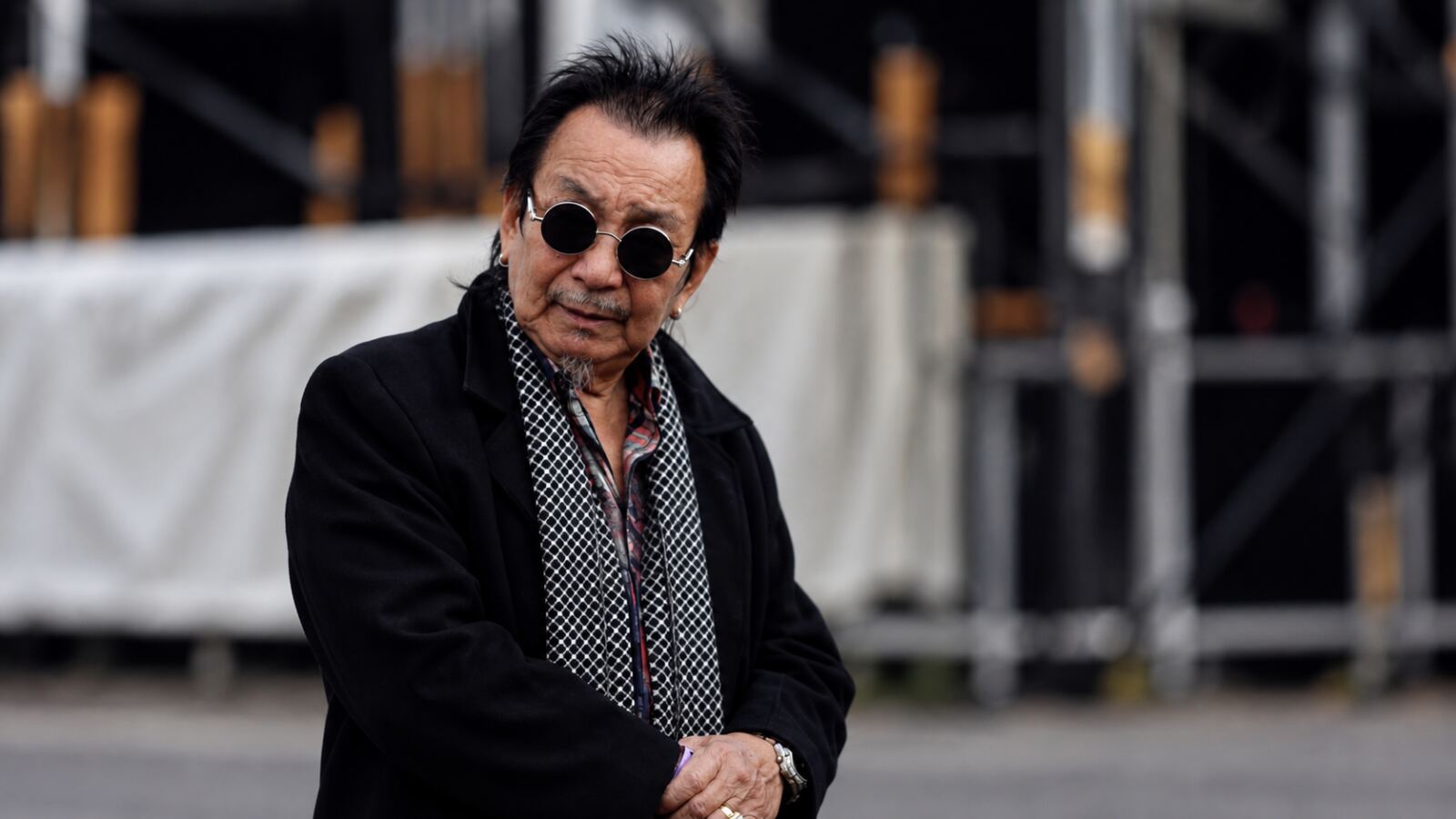 Veteran Nepali drummer in a black coat and round sunglasses