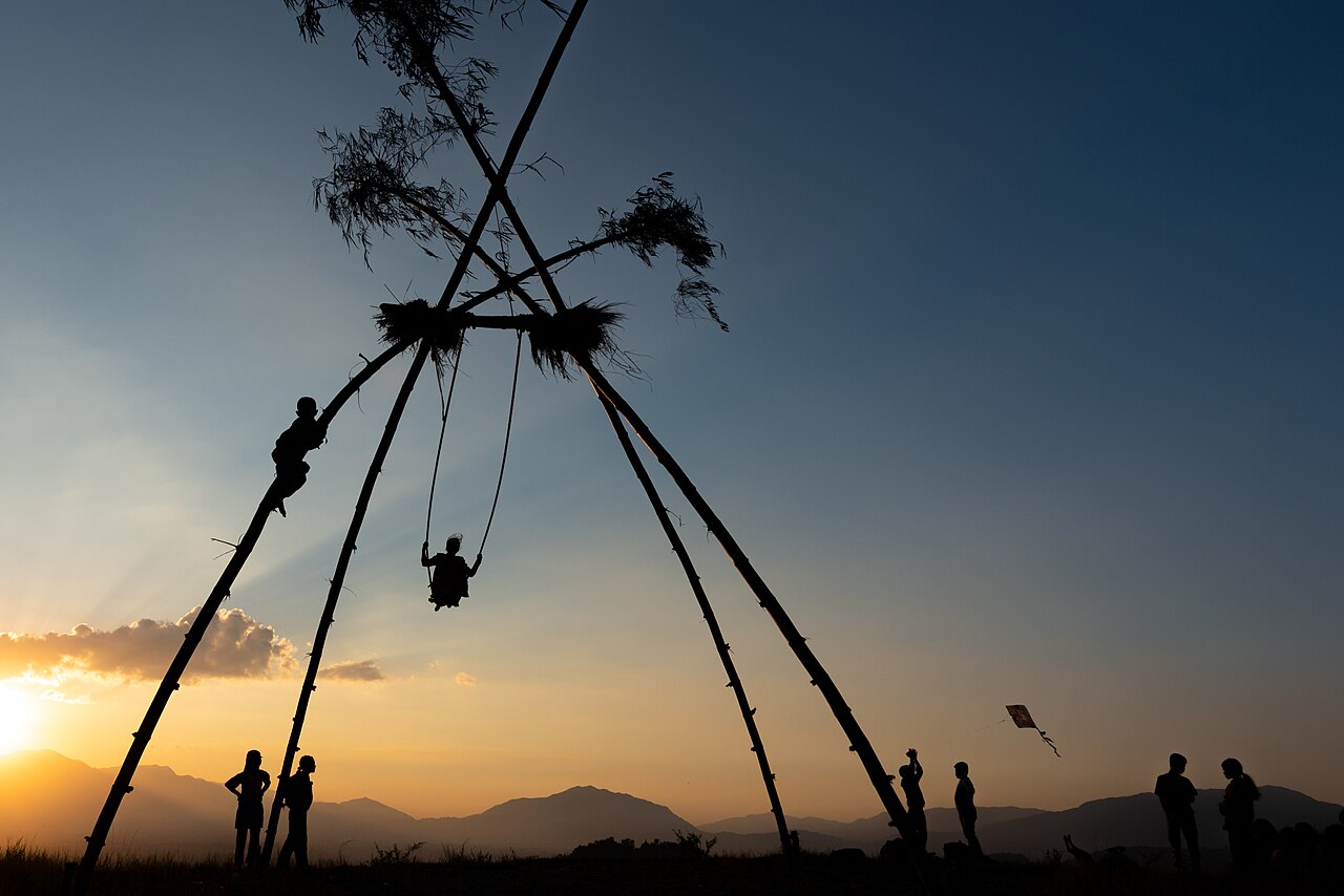 People on a bamboo swing with kite flying at sunset during Dashain in Nepal