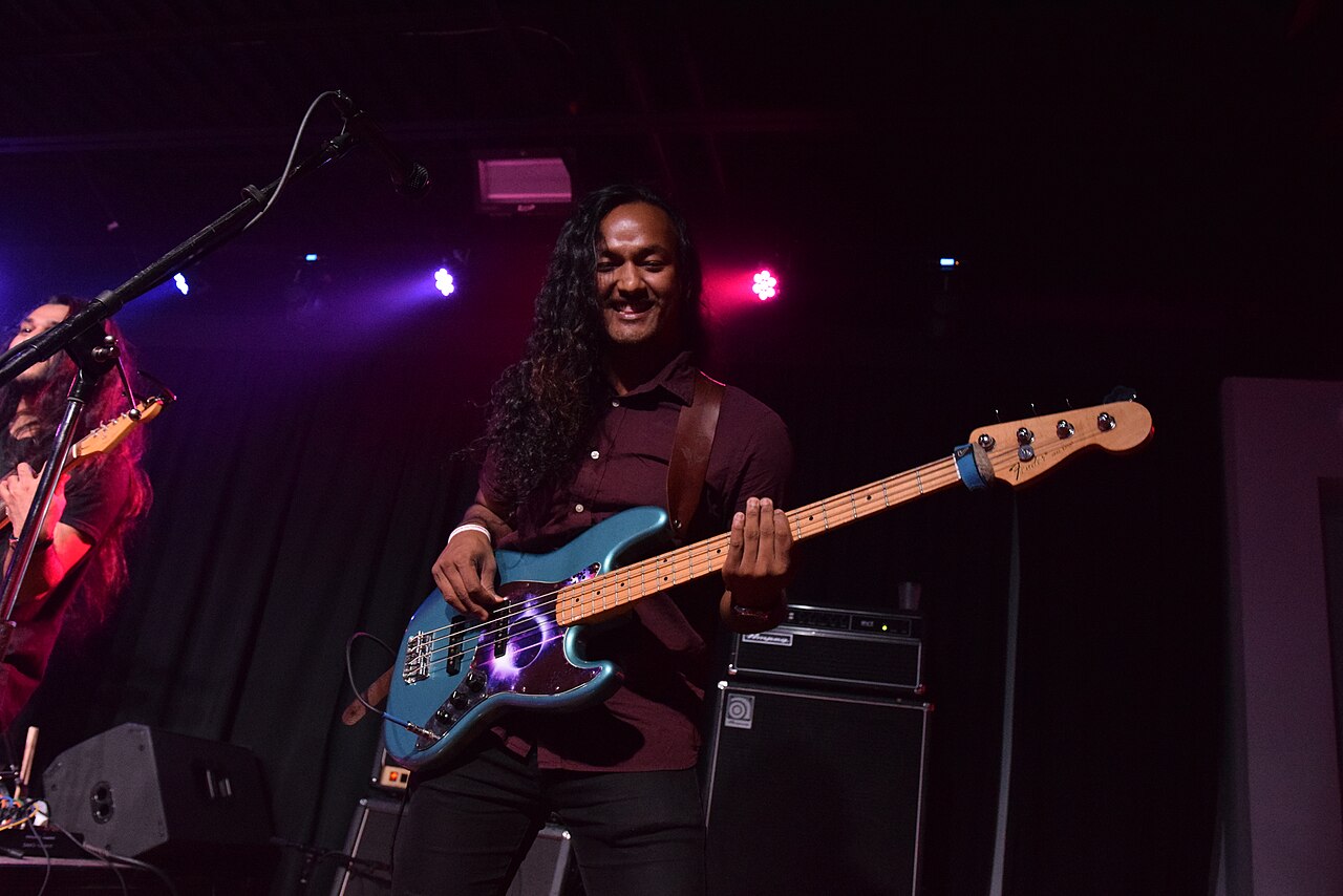 A bassist from Nepal's The Edge Band onstage with blue electric bass