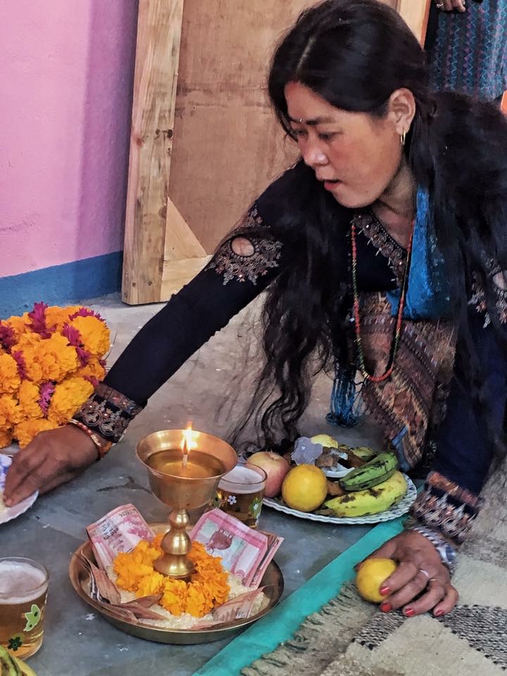 Nepali woman preparing a traditional Tihar festival puja with an oil lamp and fruit