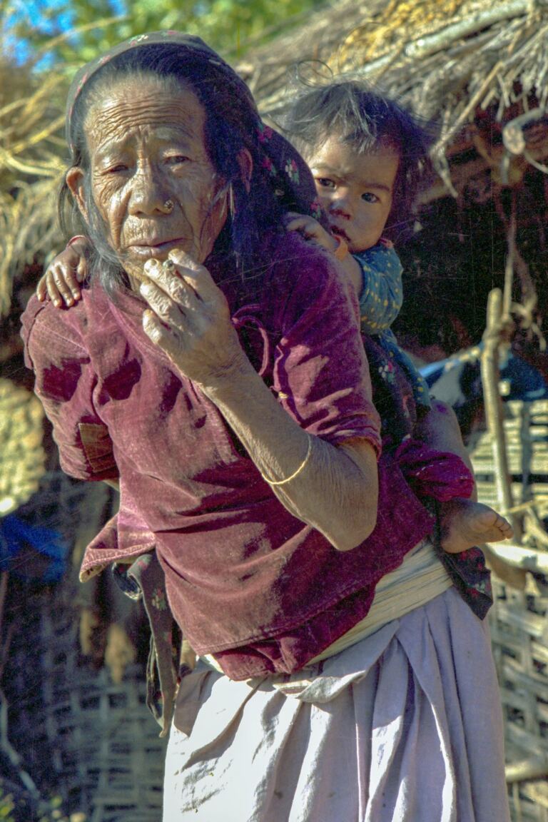 Nepali grandmother carrying a young child, representing family ties across generations and migration